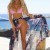 escort rubia de caderas prominentes en bikini tomando sol en la playa