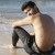 escort gay sentado en la orilla del mar